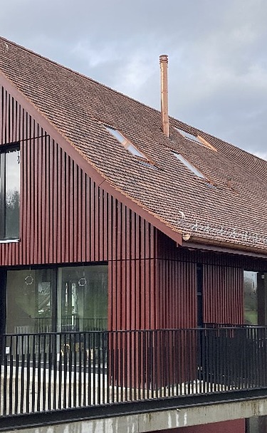 Foto von umgebautes Bauernhaus mit Holzverkleidung in dunkelrot