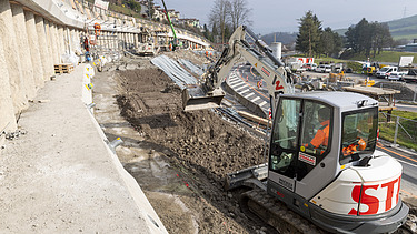 Weisser Bagger auf der Baustelle am Baggern