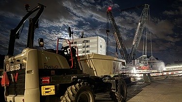 STRABAG Dumper steht vor der Schaffhauserstrassen Brücke im Hintergrund der 750 Tonnen Raupenkran