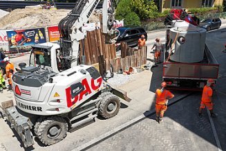 Bohrer vor einer Reihe von Stahlträgern der Rüphlwand.