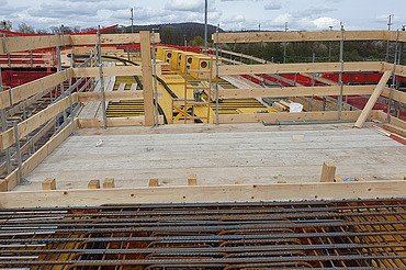 Nachtaufnahme einer STRABAG-Baustelle. Ein grosser Kran steht beleuchtet neben einem Wohnhaus unter dem klaren Nachthimmel.