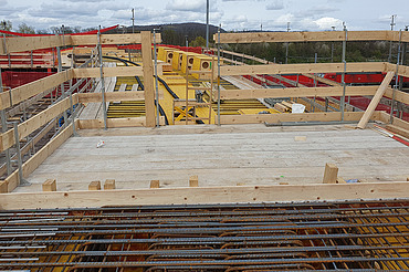 Nachtaufnahme einer STRABAG-Baustelle. Ein grosser Kran steht beleuchtet neben einem Wohnhaus unter dem klaren Nachthimmel.