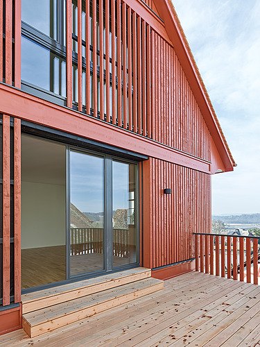 Foto von Balkon aus hellem Holz und Hausverkleidung in rot-braunem Holz