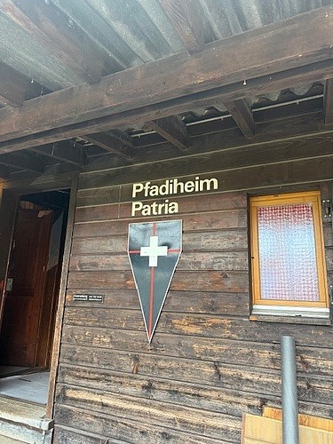 Blick auf die Holzfassade des Pfadiheims an der gerade ein Lernender dabei ist die neuen Holz Latten für die Fassade zusammenzustecken