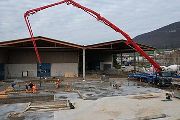 Die Baustelle «Erweiterung Bourquin» mit einem grossen, roten Betonpumpen-Lastwagen, der Beton für die Gebäudeerweiterung liefert.