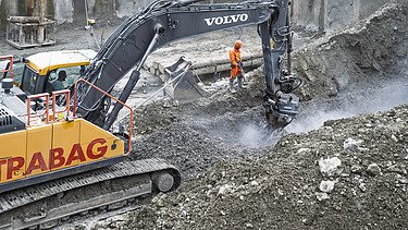 Bagger beim Abtrag von Felsgestein in der Baugrube