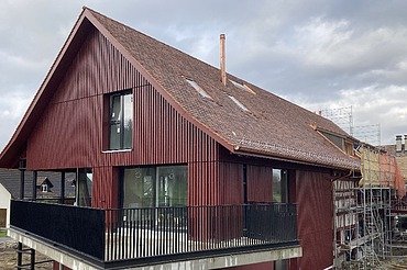 Foto von umgebautes Bauernhaus mit Holzverkleidung in dunkelrot