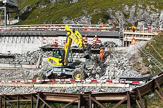 Drohnenaufnahme der Baustelle mit drei Mitarbeitenden wenig unterhalb der Fahrbahn