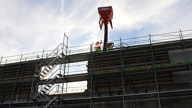 Foto von Rohbau mit Gerüst und Beton vom Kran