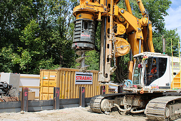 Bohrer vor einer Reihe von Stahlträgern der Rüphlwand.