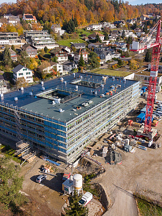 Luftaufnahme einer Baustelle mit Turmdrehkran in einem Wohngebiet.