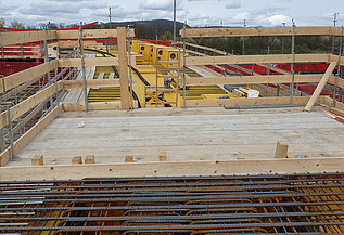 Nachtaufnahme einer STRABAG-Baustelle. Ein grosser Kran steht beleuchtet neben einem Wohnhaus unter dem klaren Nachthimmel.