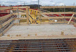 Nachtaufnahme einer STRABAG-Baustelle. Ein grosser Kran steht beleuchtet neben einem Wohnhaus unter dem klaren Nachthimmel.
