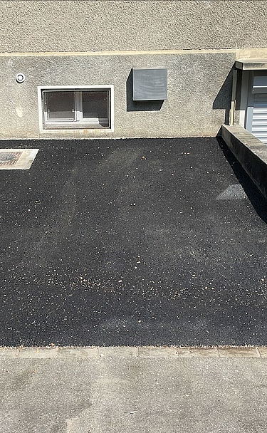 Nachtaufnahme einer STRABAG-Baustelle. Ein grosser Kran steht beleuchtet neben einem Wohnhaus unter dem klaren Nachthimmel.