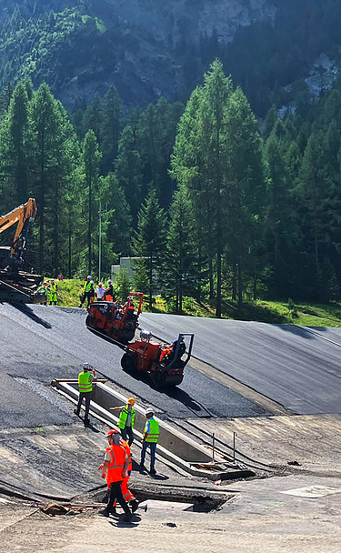 Perspektive aus grösserer Distanz, mit Baumaschinen und Mitarbeitenden im Bildmittelpunkt
