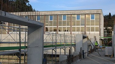 Foto vom Rohbau bis zur hälfte Hoch mit alter Schule im Hintergrund