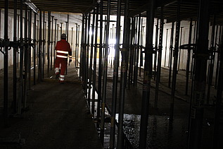 Arbeiten in der Baustelle, dunkel, ein Bauarbeiter von hinten