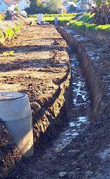 Nachtaufnahme einer STRABAG-Baustelle. Ein grosser Kran steht beleuchtet neben einem Wohnhaus unter dem klaren Nachthimmel.